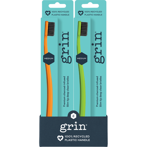 Two GRIN toothbrushes in packaging with teal and navy design.